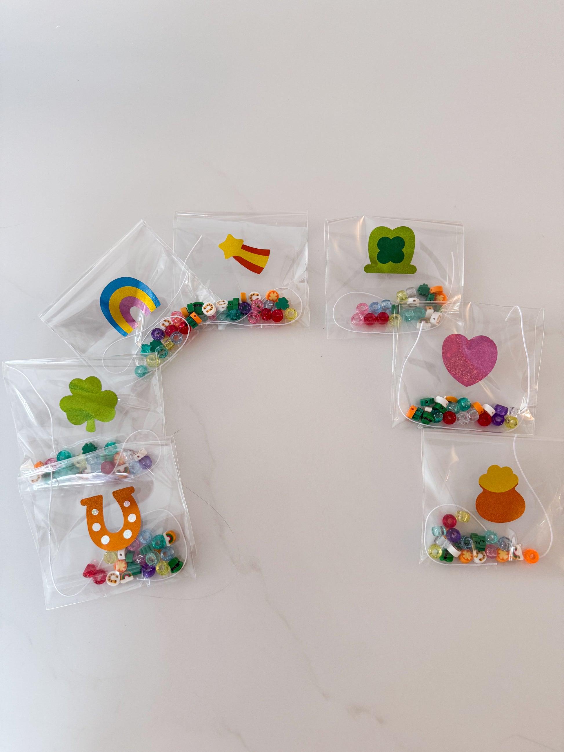 Rainbow-shaped lucky charm bracelet kits arranged for St. Patrick’s Day kids craft activity