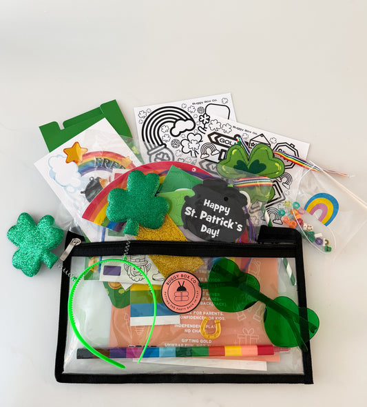 Flat lay of Lucky Bug Buggy Bag St. Patrick’s Day activity kit for kids including leprechaun trap, crafts, bracelet kit, rainbow crayon and festive accessories
